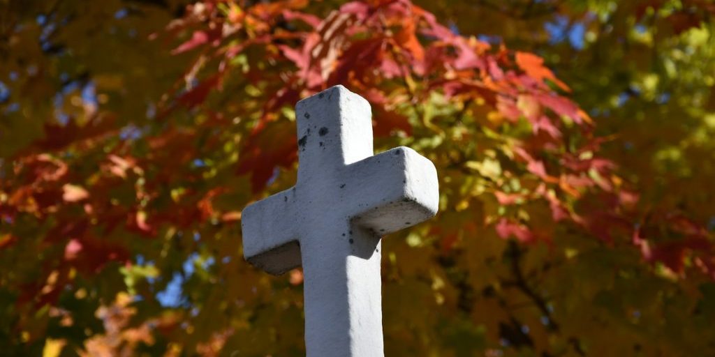 photo by claude laprise a white cross sitting in front of a tree
