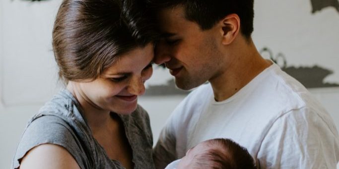 a man and woman holding a baby in their arms